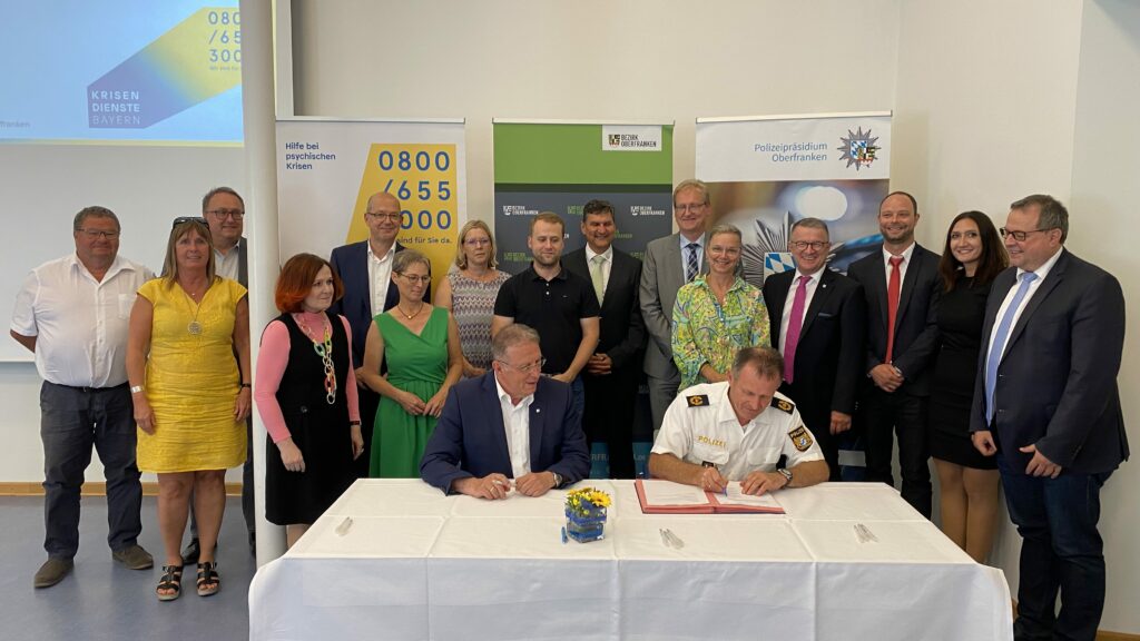 Henry Schramm, Bezirkstagspräsident von Oberfranken (links) unterschreibt die Kooperationsvereinbarung mit der Polizei.